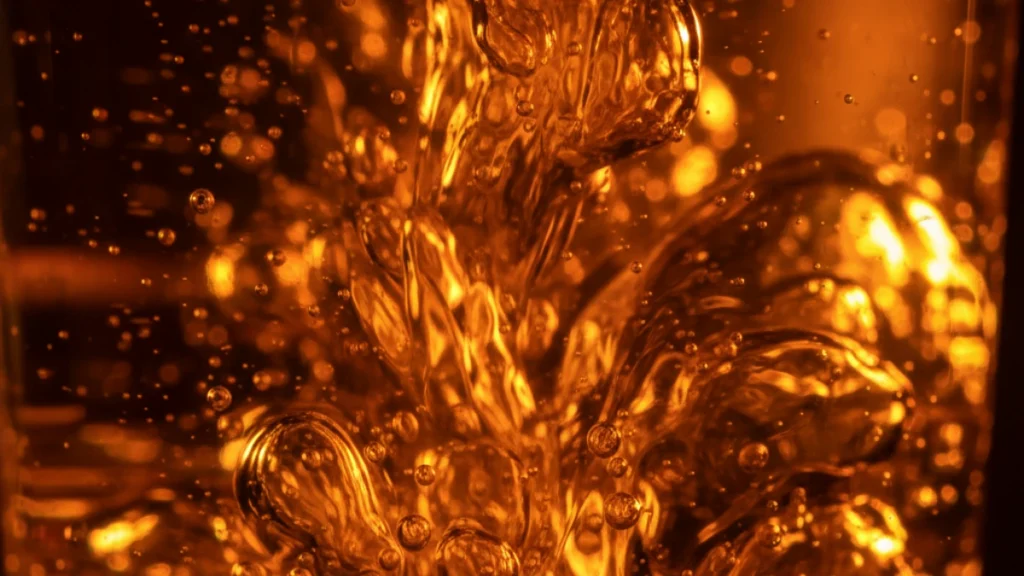 Macro photography of swirling amber and orange crystalline liquid with microscopic bubbles, symbolizing the caustic yet vibrant gastric environment